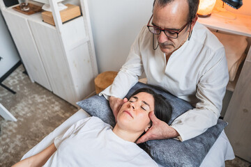Therapist providing craniosacral therapy by gently cradling a patient head for relaxation.