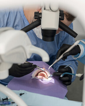 Dentist's work. Grinding patient's teeth. process of dental treatment. mouth dilator on patient during dental treatment. Dental treatment using microscope. Dental instrument. Front view.
