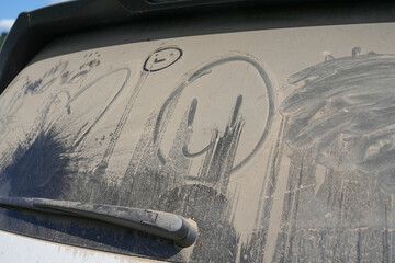 dust and dirt on the rear window of a car with funny drawings