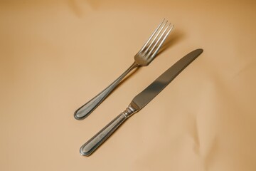 Stainless steel utensils on beige backdrop viewed from a 45 degree angle