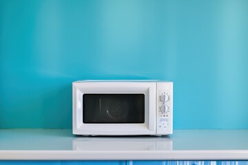 Fototapeta premium White microwave near blue wall on counter