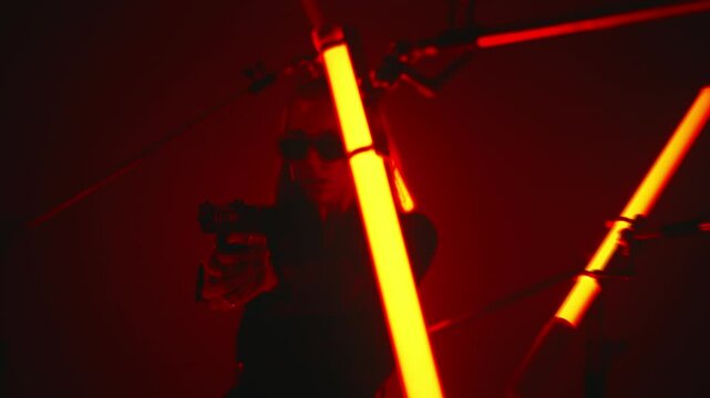 Dangerous female hitman aiming with a handgun in a dark room