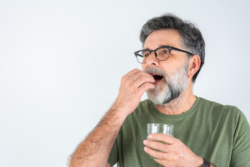 Obraz premium Handsome mature man taking pill isolated