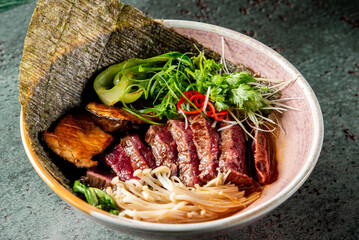 bowl of Asian noodles with vegetables, garnished with herbs. dish is presented in a rustic setting, emphasizing its fresh and appetizing appearance. Ideal for food-related content and culinary themes.