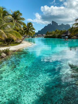 View of the Mount Otemanu through turquoise lagoon, palm trees and overwater bungalows on Bora Bora island, Tahiti, French Polynesia, South Pacific