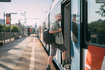 A man gets on a train on the platform. A young guy, a passenger with a backpack, enters the carriage from a high platform