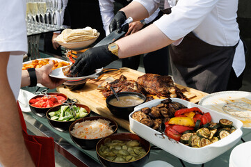 The cook is preparing meat. Cropped chef preparing food, meal, in kitchen, chef cooking. Chef decorating dish, closeup