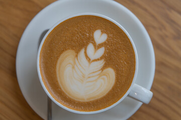 Table top view of white porcelain cup of cappuccino with latte art 