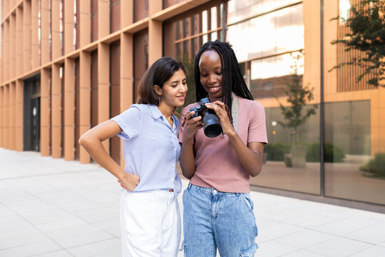 Students reviewing photos on camera outside university