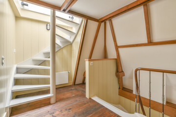 Cozy attic room with wooden beams and white staircase