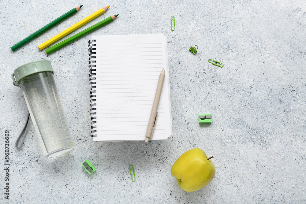 Wall mural Blank notebook with stationery and bottle of water on grunge white background