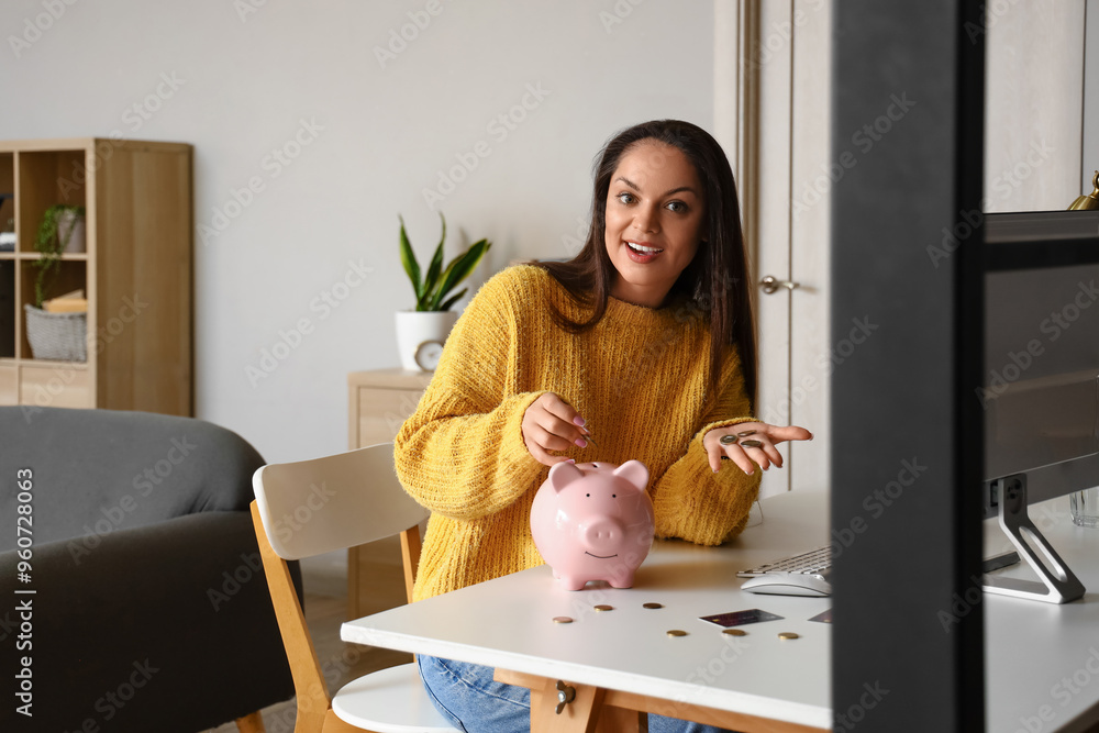 Canvas Prints Young woman putting coin in piggy bank at home