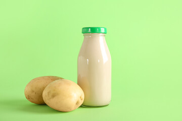 Bottle of tasty potato milk on green background