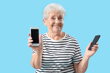 Senior woman with mobile phones on blue background