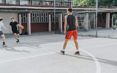 Group of friends playing basketball at an old neighborhood court, enjoying a sunny day and showcasing energy and teamwork in a casual outdoor setting.