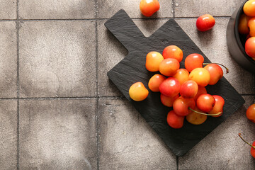 Board with sweet yellow cherries on grey tile table