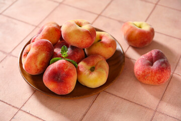 Wooden plate with sweet fig peaches and mint on pink tile background