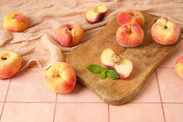 Wooden board with sweet fig peaches and mint on pink tile table