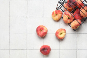 Basket with sweet fig peaches on white tile background