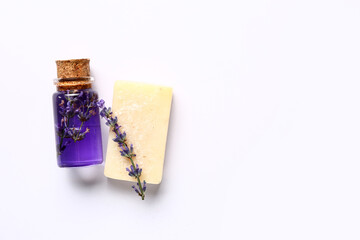 Bottle of lavender essential oil and soap bar on white background