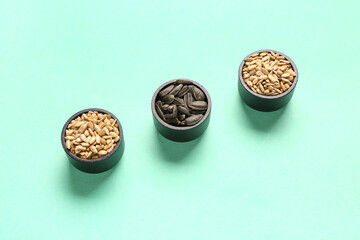 Bowls with sunflower seeds on blue background