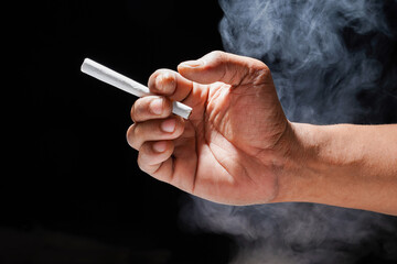 hand holding a cigarette on black background for copy space, close up of hand holding a cigarette.
