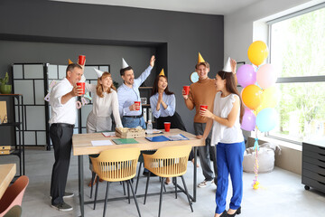 Business people with cups at birthday party in office