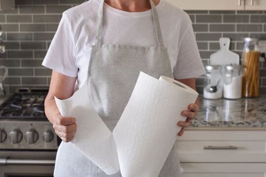 Woman is tearing a piece of paper towel in a kitchen at home