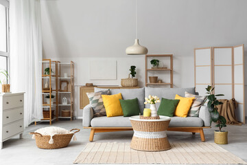 Sofa, wicker basket and table in interior of light cozy living room