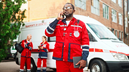 Camera moving back from African American professional male doctor in glasses talking on smartphone...