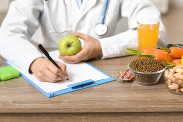 Young female nutritionist with clipboard and healthy food writing diet plan in office, closeup
