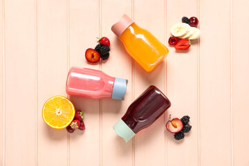 Sports bottles of fresh juice with different fruits on pink wooden background