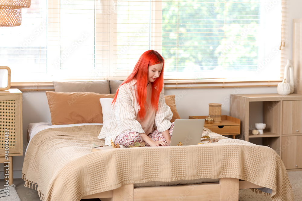 Sticker beautiful young happy woman with laptop and autumn leaves sitting in bedroom at home