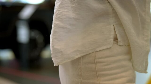 Closeup cropped shot of unrecognizable woman pulling wad of bills out of back pocket of pants, showcasing casual moment of handling money in indoor setting. Shooting in slow motion.