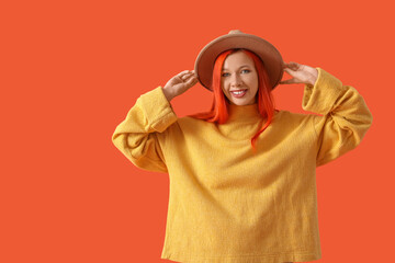 Beautiful young happy woman in autumn outfit on orange background