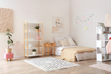 Interior of light teenager's room with bed, table and shelf unit