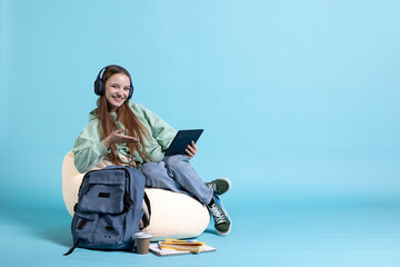 Smiling teenager wearing headphones having fun, using tablet, being entertained. Jolly person...