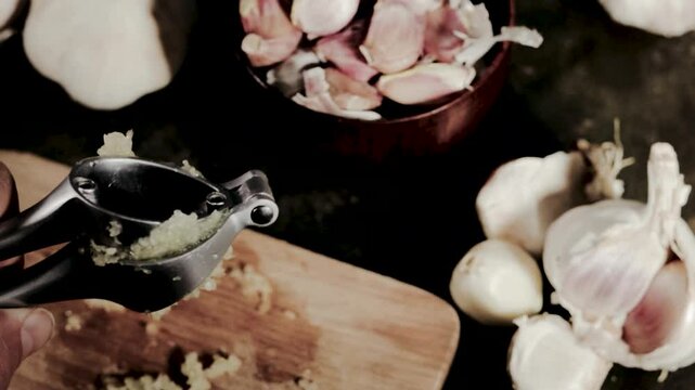 Squeezing garlic with metal garlic press. Food preparing,