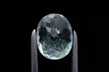 Captivating Close-Up of a Faceted Gemstone Held by Precision Tweezers Against a Dark Background