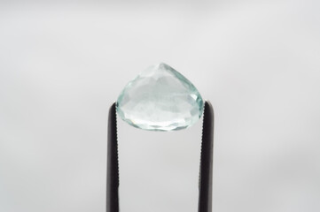 Glistening Aquamarine Gemstone Held by Precision Tweezers on Soft Background