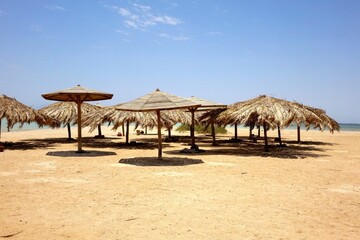 Serene Beach Setting With Straw Umbrellas at Paradise Island Hurghada on the Red Sea