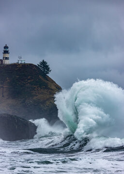 Waves crash below lighthouse at Cape Disappointment State Park, Washington State, USA.
