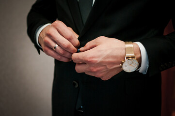 Elegant Preparation: Man Buttoning Suit Jacket with Sophisticated Timepiece