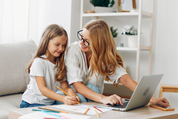 Mother and daughter bonding on the couch while using a laptop, sharing a moment of learning and fun...