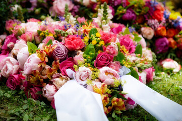 vibrant colorful funeral wreath with bow on a grave after a funeral