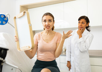 Portrait of unhappy worried woman after cosmetological procedure at clinic of esthetic medicine