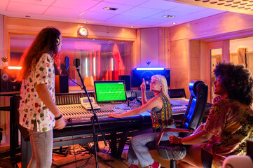 Singer singing a song while the producer is working on a soundboard in a studio