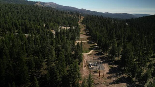 Aerial of powerlines through Okanogan Mountains and forest in Washington in summer