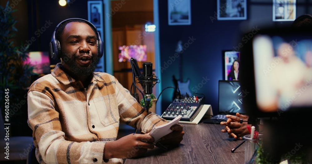 Poster bipoc man on podcast conversating with guest during marathon stream for charitable cause. host in ap