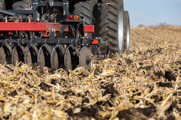 Tractor pulling chisel plow implement in farm field. Farm tillage, erosion control, and soil...